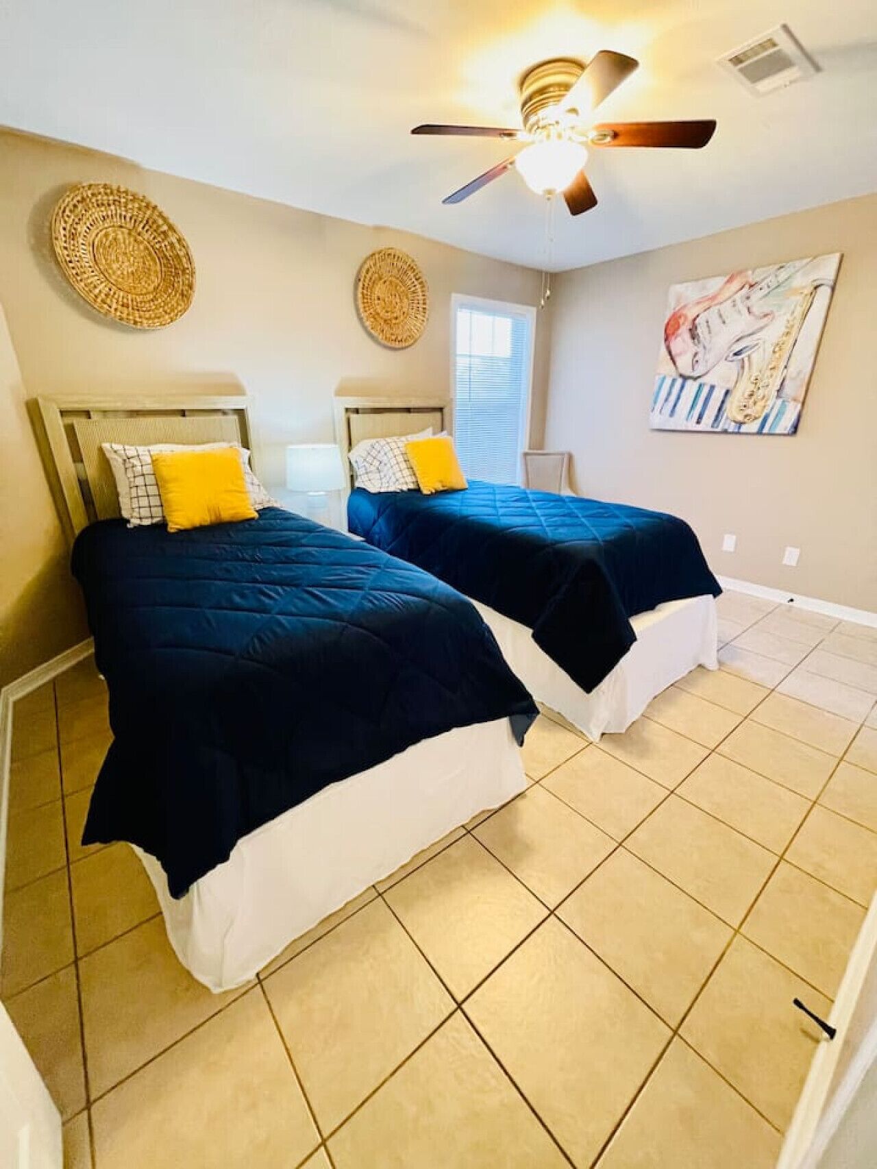 A bedroom with two beds, a ceiling fan, and a window.