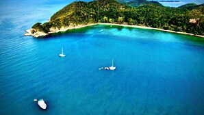 An aerial view of a coastal area with clear turquoise waters, a small island with dense greenery, and boats anchored near the shore. - Rimba Resort - Dive Centre and Spa (Sibu Island)