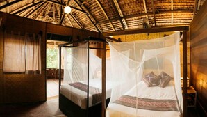 A room with a thatched roof, wooden walls, and a bed with a mosquito net. - Rimba Resort - Dive Centre and Spa (Sibu Island)