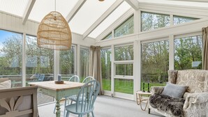 Une pièce spacieuse avec une grande fenêtre, une table à manger, des chaises, un canapé et un luminaire suspendu.