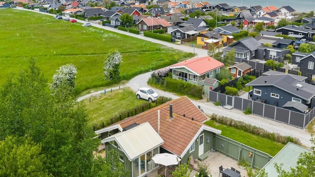 Un quartier résidentiel avec des maisons, un champ d’herbe et une vue sur la mer.