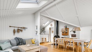 Un vaste espace de vie doté d’un plancher en bois, d’un canapé, d’une table à manger avec des chaises et d’un coin cuisine équipé d’une cuisinière.