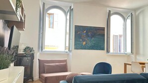 A room with a large window, a painting of boats, a sofa, and a desk. - La Bella Vita Navona (Roma)