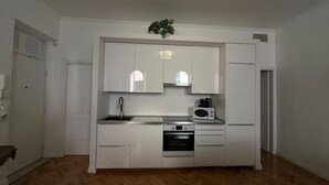 A compact kitchen with white cabinets, a microwave, a sink, and a stove. - La Bella Vita Navona (Roma)