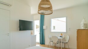 A bedroom with a bed, a TV, a desk with chairs, a window, and a door. - Ideal stay, with beaches, ponds and tramway just around the corner! Apt 2 (Pérols)