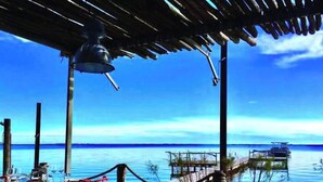 An outdoor dining area with tables and chairs, a hanging light fixture, and a view of the water. - Ideal stay, with beaches, ponds and tramway just around the corner! Apt 2 (Pérols)
