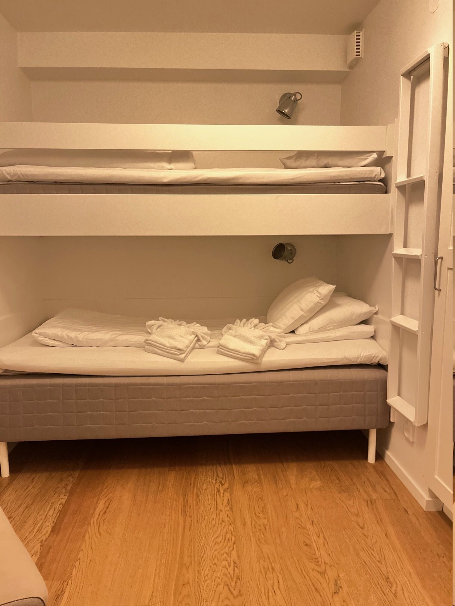 A bunk bed with a lower bunk, a small shelf above the lower bunk, and a door on the right side.
