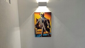 A room with a wooden floor, a white textured wall, and a painting of a cheetah in a suit. - Elodia Luxury Apartment - Wi-Fi, Smart TV, Terrace, Kitchen, Towels (Heidenheim an der Brenz)