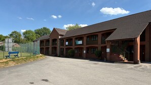 A multi-story brick building with a parking lot in front. - Tollgate Hotel (Stoke-on-Trent)