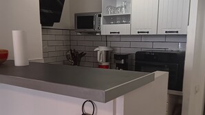 Una cocina con armarios blancos, microondas, cafetera y tostadora.