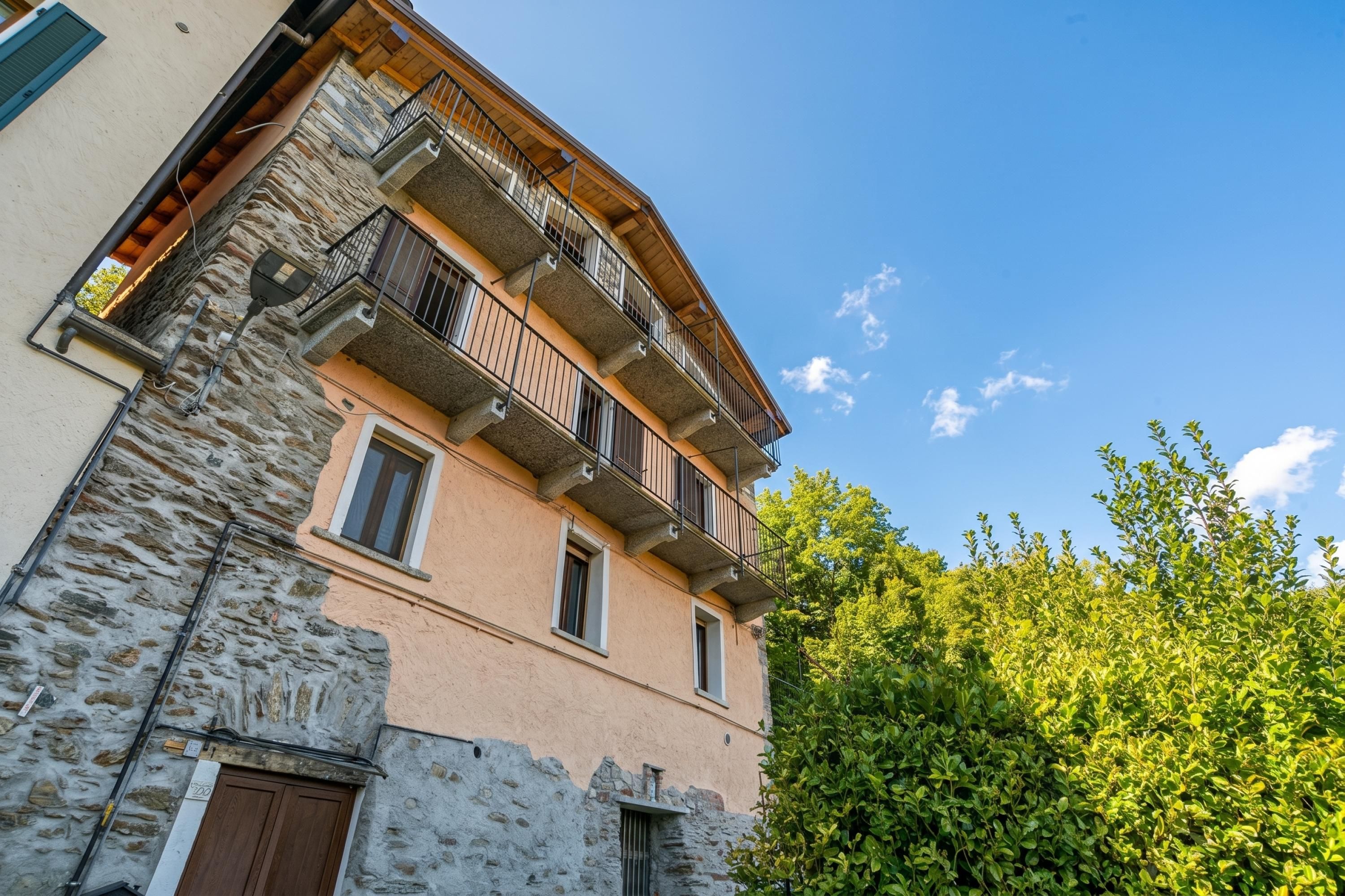A multi-story building with stone and plaster exterior walls, balconies, and a clear blue sky.