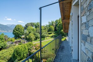 A balcony with a view of a lake and mountains, stone walls, and a metal railing. - Cremia Dreamhouse (Cremia)