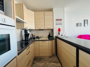 Eine kleine Küche mit Holzausstattung, einer Kaffeemaschine, einer roten Lavalampe und einem Waschbecken.