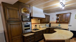 Une cuisine avec des meubles de rangement en bois, un four encastré, un four à micro-ondes, une cuisinière à gaz et un évier.