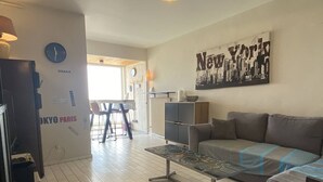 A living room with a sofa, a coffee table, a clock, and a wall with a 'New York' poster.