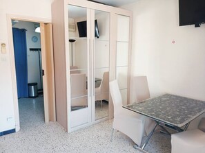 A room with a wardrobe, a table, and chairs.