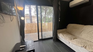 A room with a sofa, a table with a remote control, and an air conditioning unit.