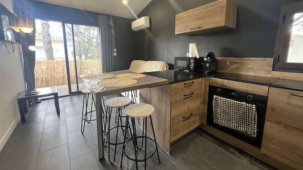 A modern kitchen with a central island, bar stools, a microwave, a coffee maker, and a dishwasher.