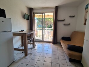 A compact room with a kitchenette, a dining area, a sofa, and a sliding glass door leading to an outdoor area. - Studio with Terrace and Parking in Canet-en-Roussillon (Canet-en-Roussillon)