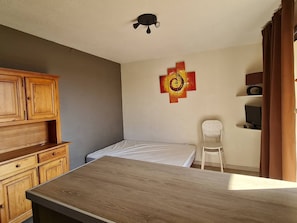 Een slaapkamer met een bed, een houten kast, een stoel, een televisie en een plafondventilator.