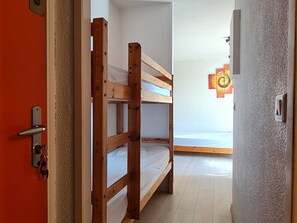 Ein Zimmer mit Etagenbetten, einer Tür mit Schlüsselsperre und einem Lichtschalter an der Wand.