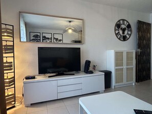 Ein modernes Wohnzimmer mit einem Flachbildfernseher, einer Kaffeemaschine und einer Uhr an der Wand.