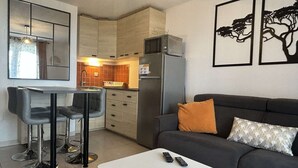 A modern living room with a sofa, a coffee table, and a kitchen area with a refrigerator and microwave. - Modern 2-room apartment with parking and Wi-Fi in Banyuls-sur-Mer (Banyuls-sur-Mer)