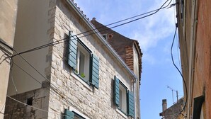 A narrow street with a stone building featuring green shutters and a motorcycle parked at the entrance. - Modern Studio in the City Center (Split)
