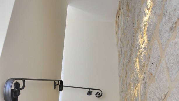 A staircase with a stone wall on one side and a light fixture on the other. - Modern Studio in the City Center (Split)