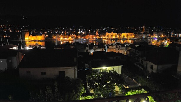 A nighttime view of a cityscape with illuminated buildings and a pool area with a blue-lit edge. - Stunning View Suite With Balcony (Trogir)