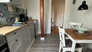 Ett kök med en träkolonn, en kaffebryggare och en matplats med ett bord och stolar.