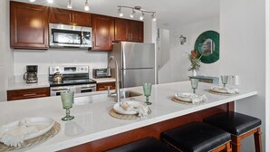 Una cocina moderna con armarios de madera, electrodomésticos de acero inoxidable y una encimera blanca.