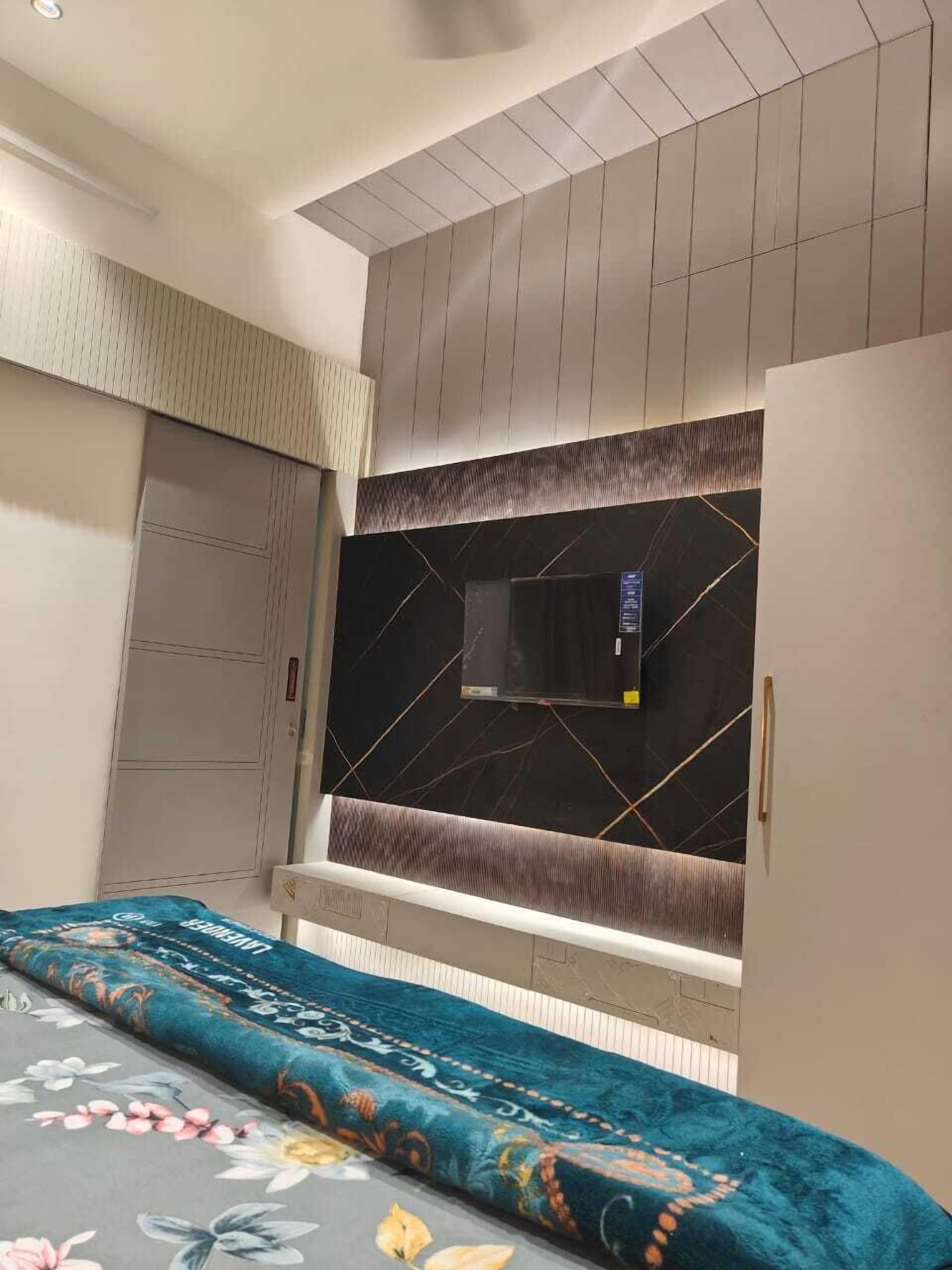 A bedroom with a bed, wardrobe, and a TV mounted on the wall.