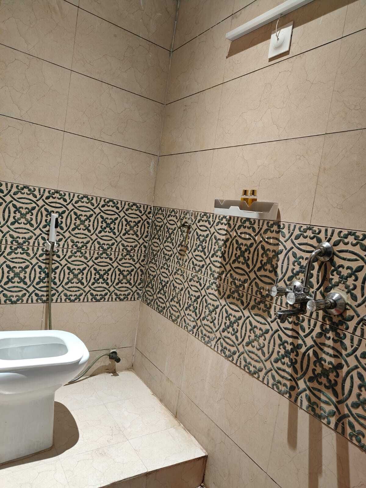 A bathroom with a toilet, a shower, and a patterned tile wall.