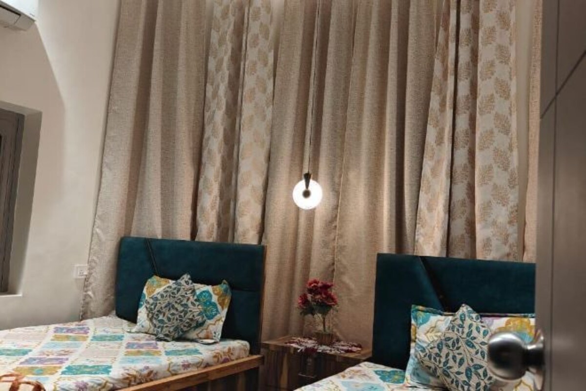 Un dormitorio con dos camas, una mesita pequeña y un jarrón decorativo.