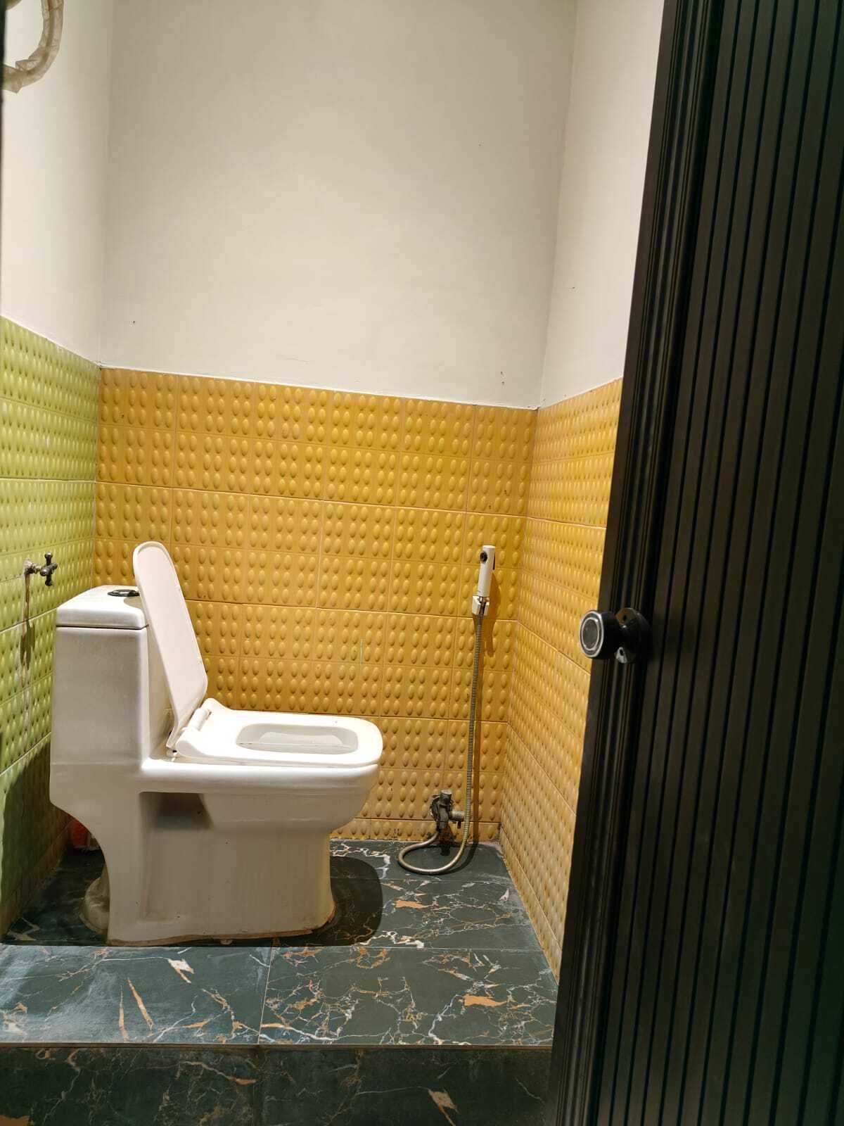A small bathroom with a toilet, a shower, and a marble floor.