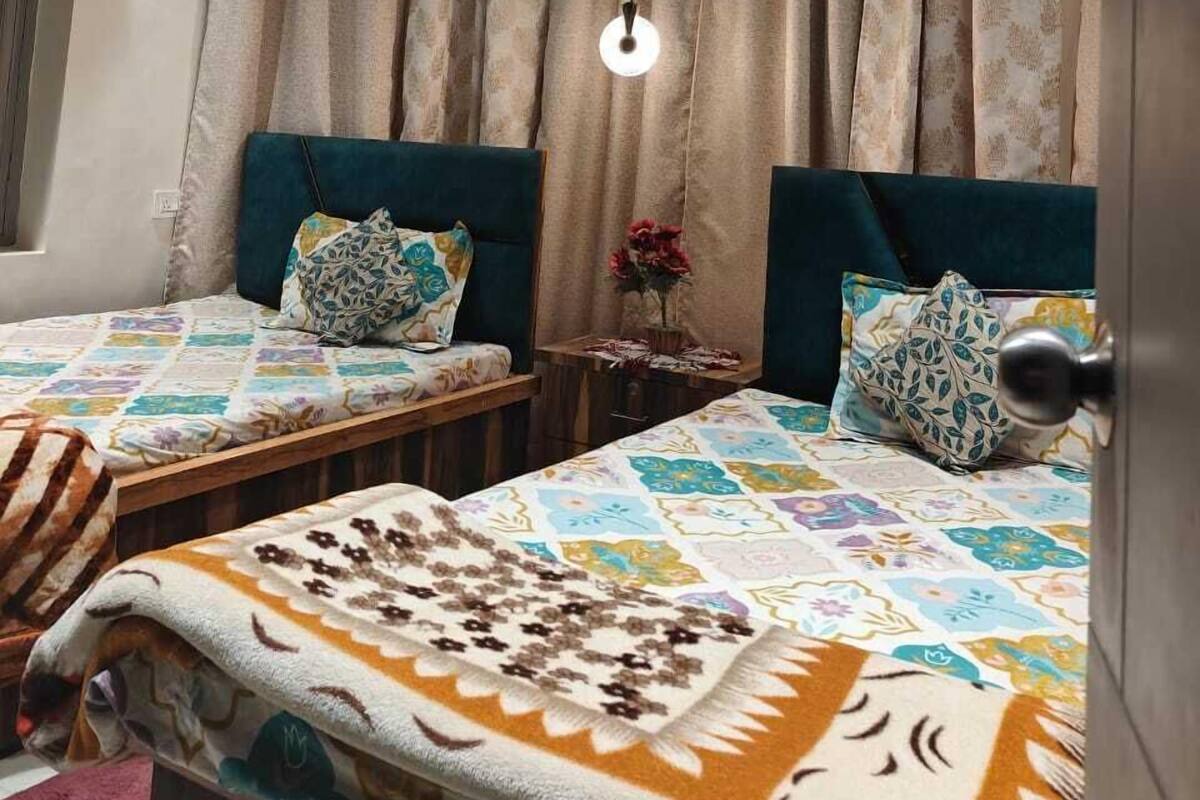A bedroom with two beds, a ceiling fan, and a light fixture.