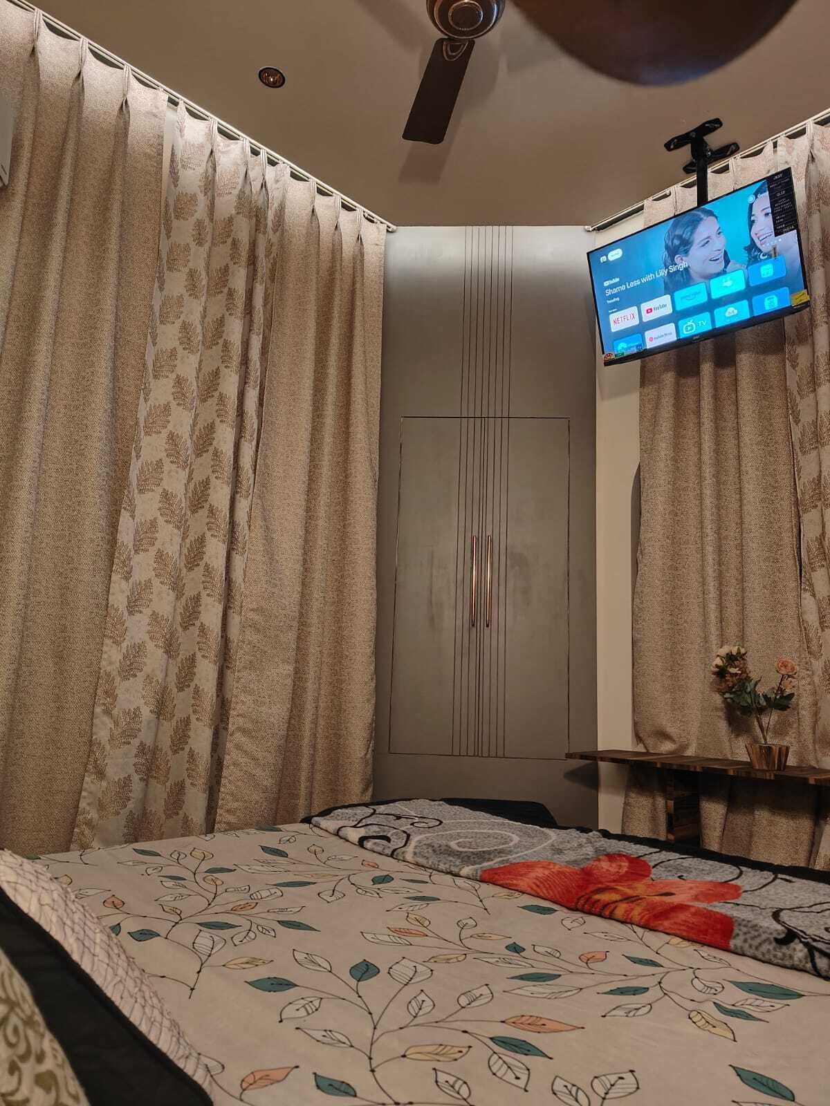 Ein Schlafzimmer mit Bett, Vorhängen, Kleiderschrank, Fernseher und Deckenventilator.