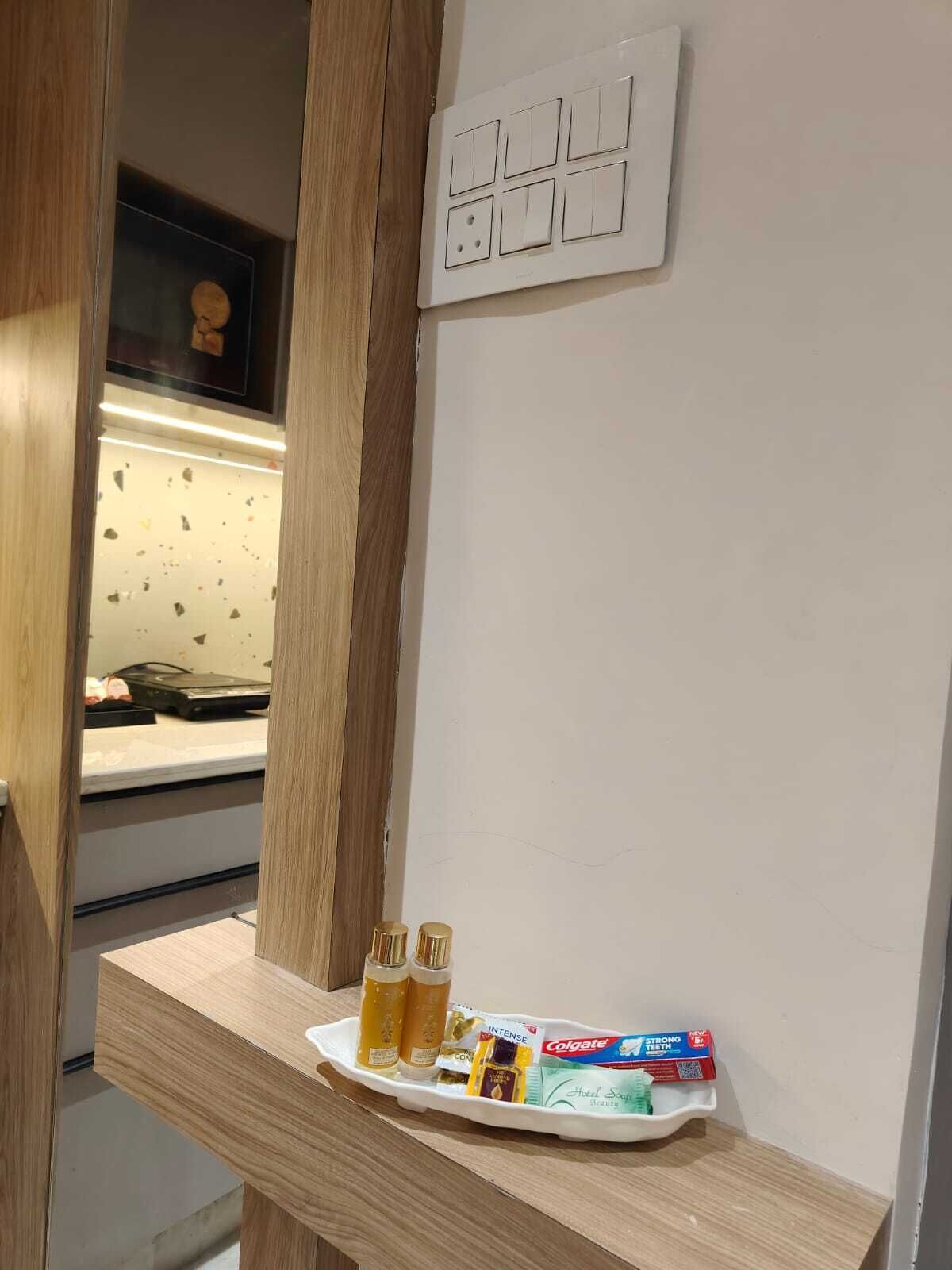 A bathroom with a wooden vanity, a sink, and a mirror. There is a tray with toiletries on the vanity.