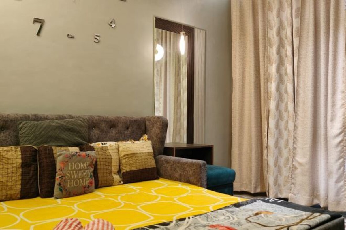 Un dormitorio con sofá cama, colcha amarilla estampada y una pared con números.