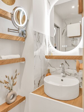 A bathroom with a round sink, a mirror, and wooden shelves. - Saint Tropez gendarme apartment (Saint-Tropez)