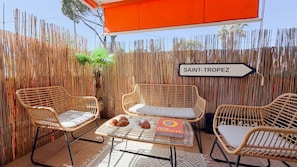Un espace extérieur aménagé avec des meubles en osier, sur lequel on peut lire l’inscription « SAINT-TROPEZ ».