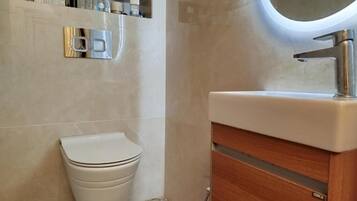 A bathroom with a toilet, a wooden cabinet, and a shelf with toiletries.