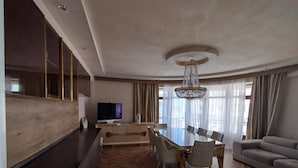 A modern living room with a dining area, a television, and a chandelier. - Baku Lake view 3 bedrooms apartment (Baku)