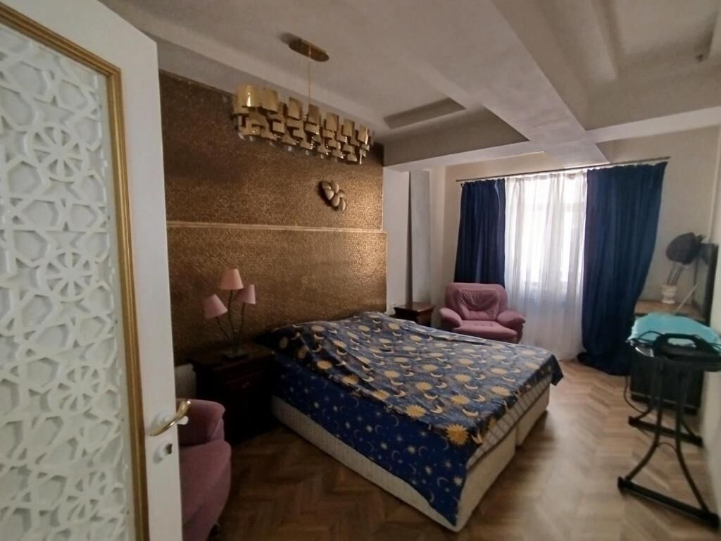 A bedroom with a bed, a chair, a desk, and a window with curtains.