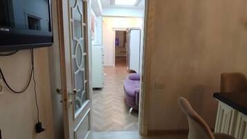 Une pièce avec un téléviseur fixé au mur, une porte donnant sur une autre pièce, une chaise et une table.