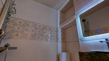 A bathroom with a shower, toilet, and a mirror.