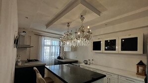 A modern kitchen with a central island, white cabinetry, and a chandelier. - Baku Lake view 3 bedrooms apartment (Baku)