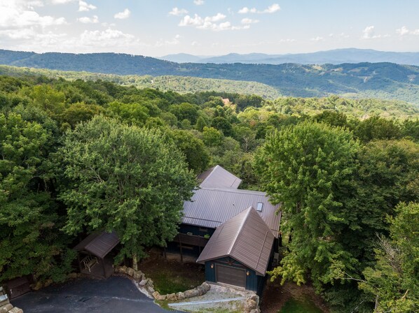A house surrounded by dense forest with a view of distant mountains.