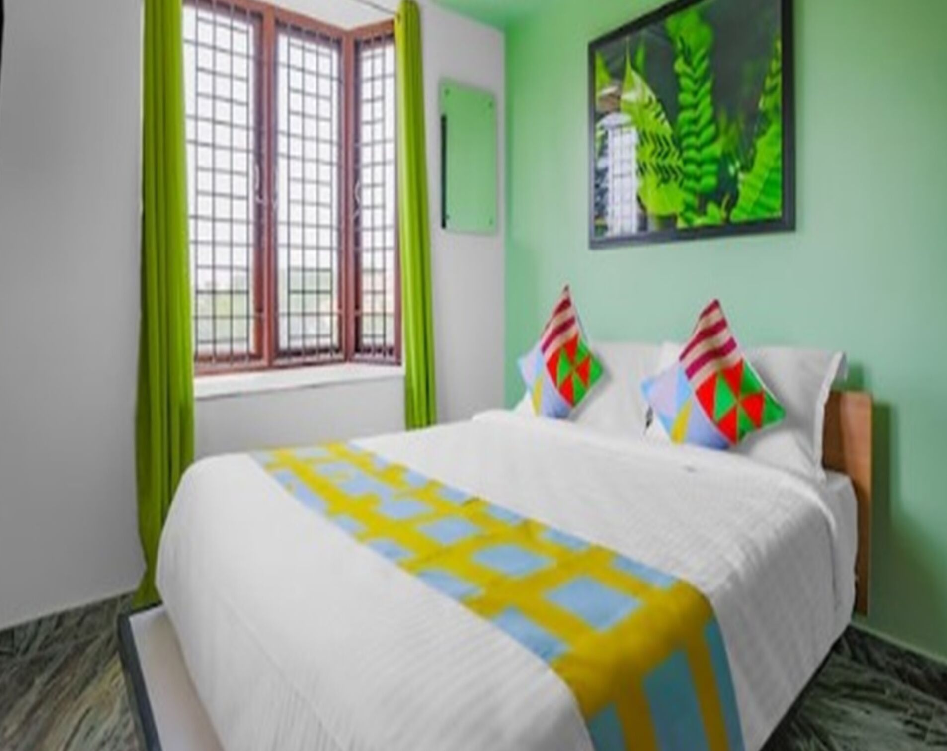 A bedroom with a bed, green curtains, a window, and a painting on the wall.